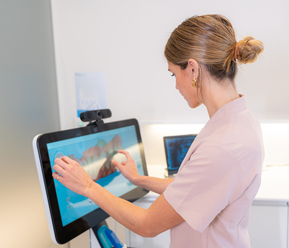 Dentist moving an impression of a row of teeth on a touchscreen
